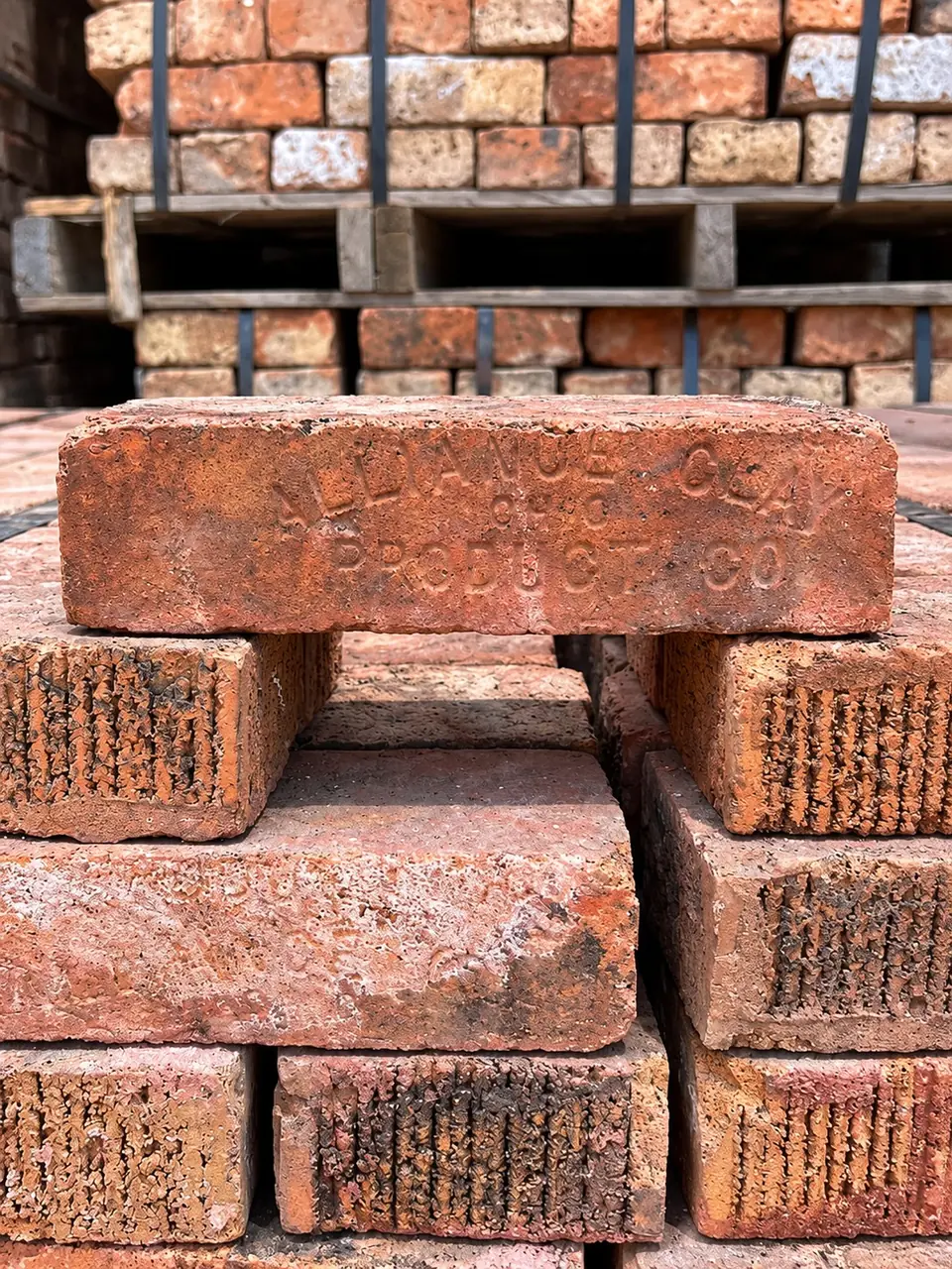 Vintage brick stamped Alliance Clay Product Co. on a stack of red brick