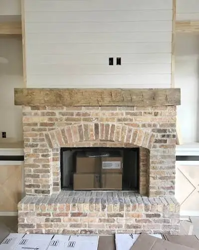 Fireplace faced in reclaimed Chicago brick with a wood beam mantel
