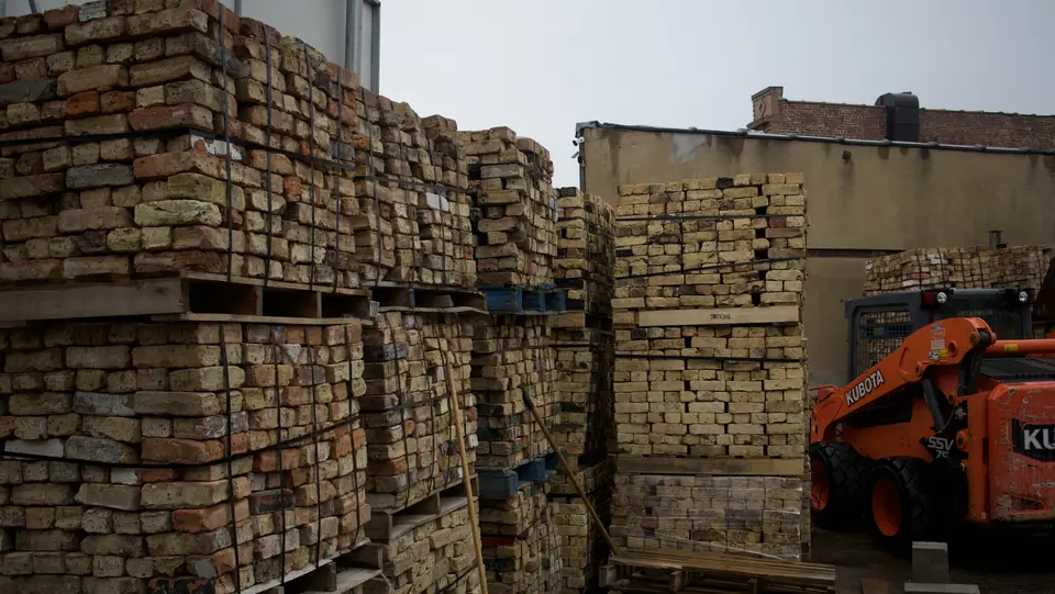Rows of stacked reclaimed Chicago brick pallets with a skid steer in the yard